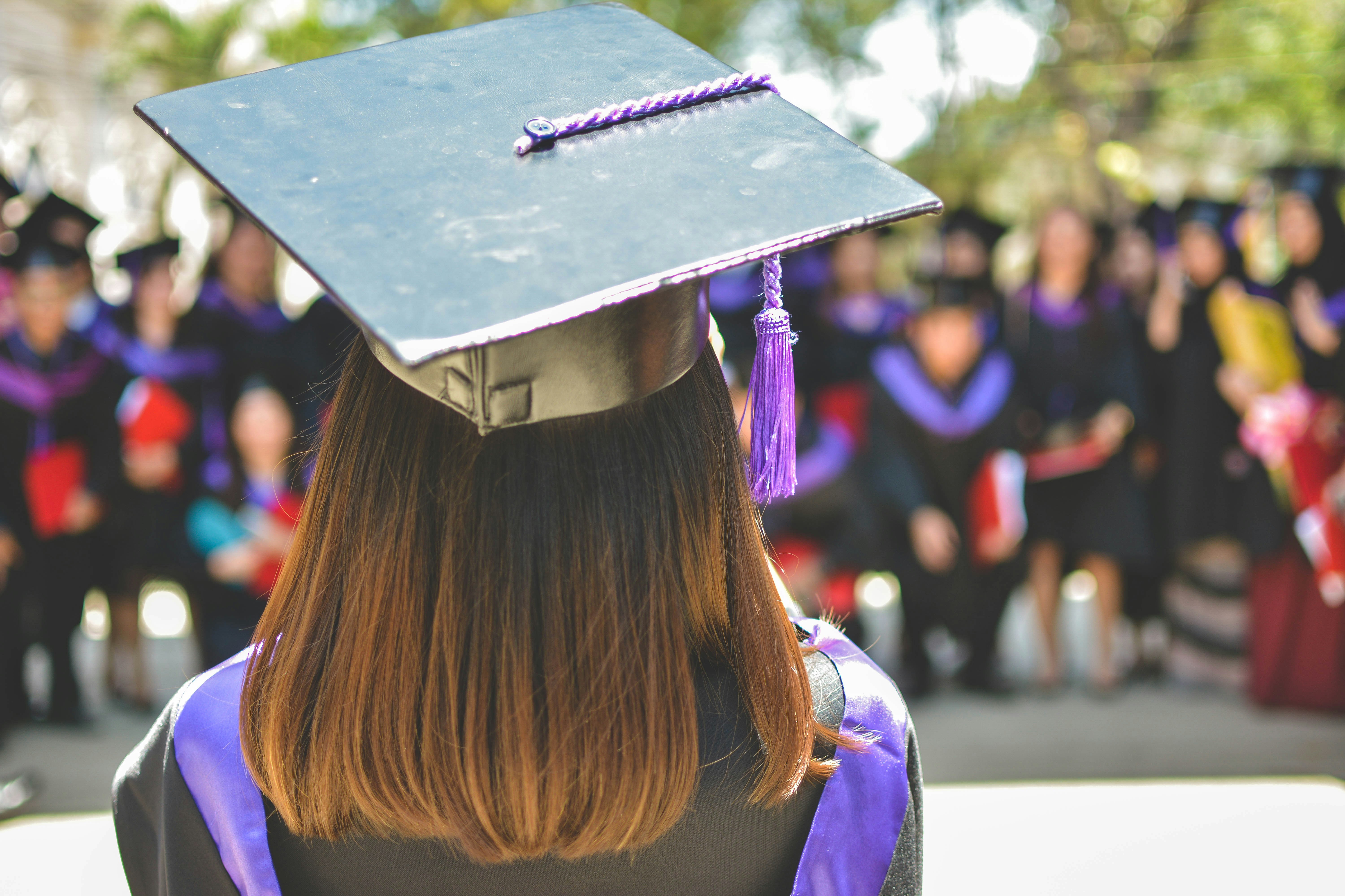 Woman facing the crowd at her graduation wearing cap and gown. 